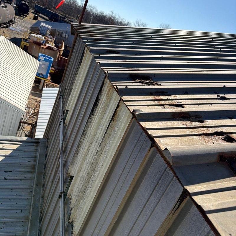 Metal roof panels with hail damage on commercial building