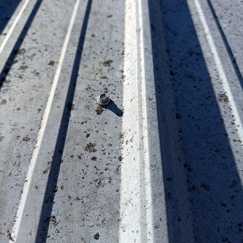 Metal roofing panel with hail damage and fastener detail