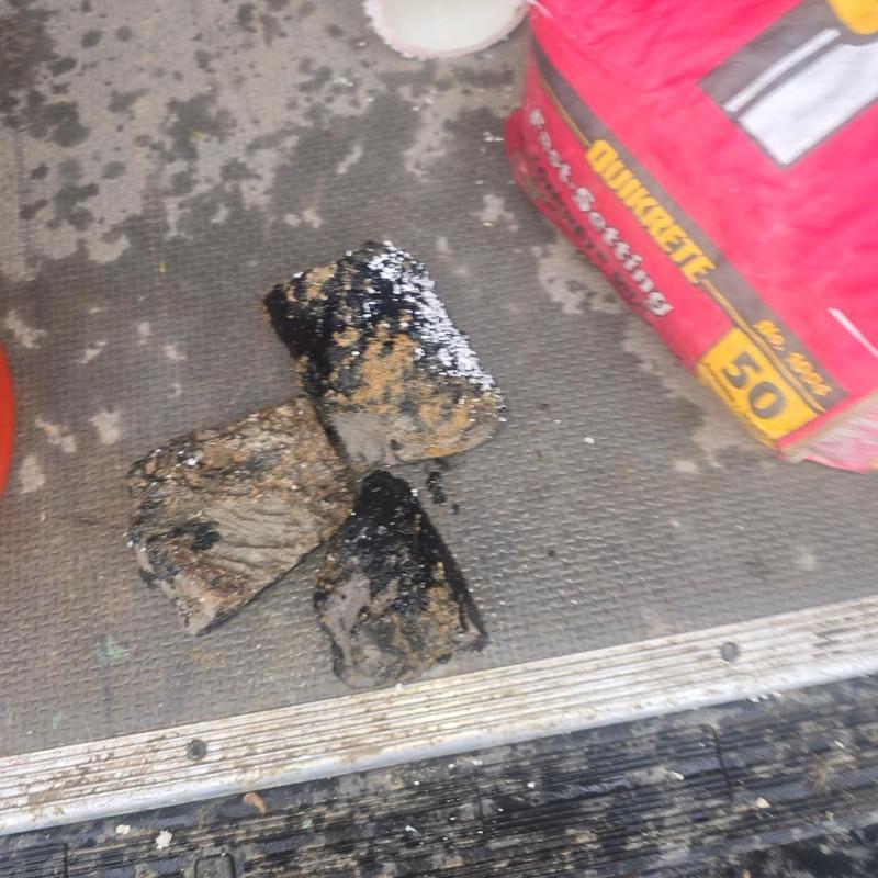 Cast iron pipe clog debris removed with cement bag nearby
