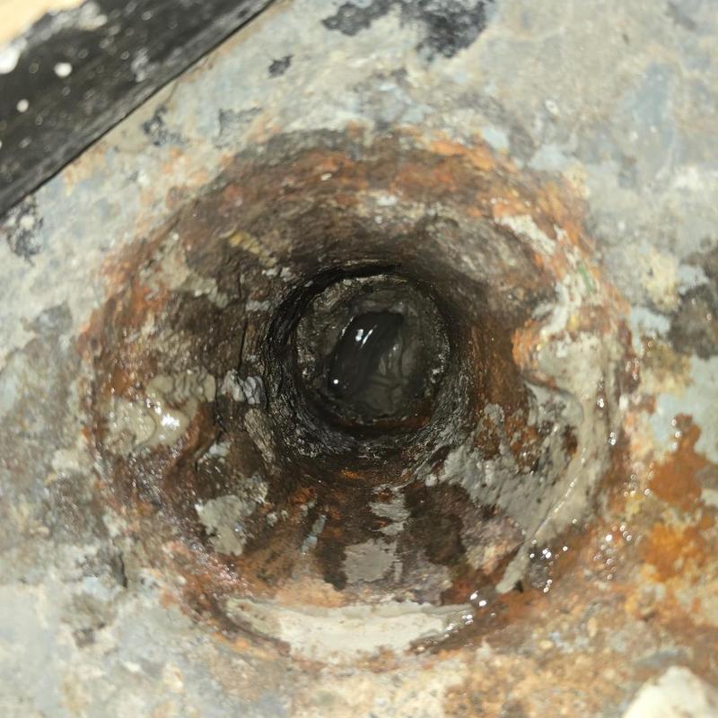 Cast iron floor drain pipe interior with corrosion and water