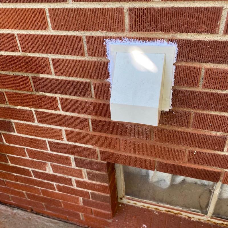 Dryer vent cover installed on brick exterior wall