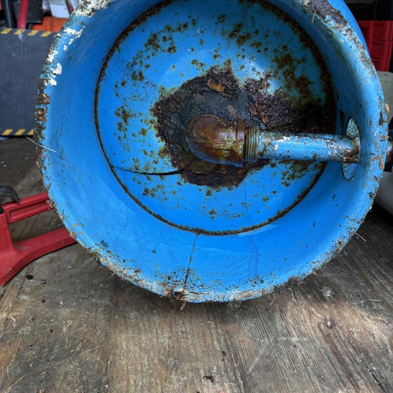 Rust-damaged bottom of well tank with pipe connection