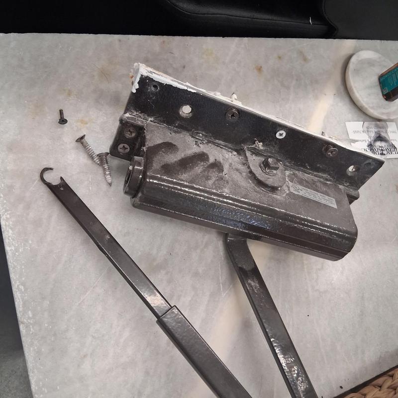Door closer with detached arm and screws on table
