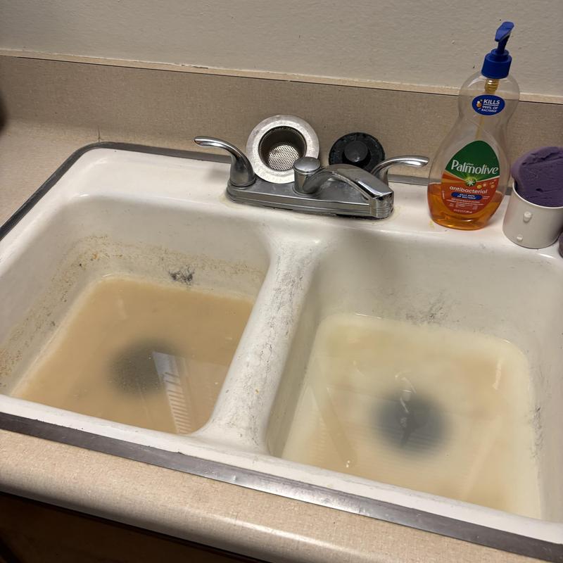 Kitchen sink with clogged, standing water and soap bottle