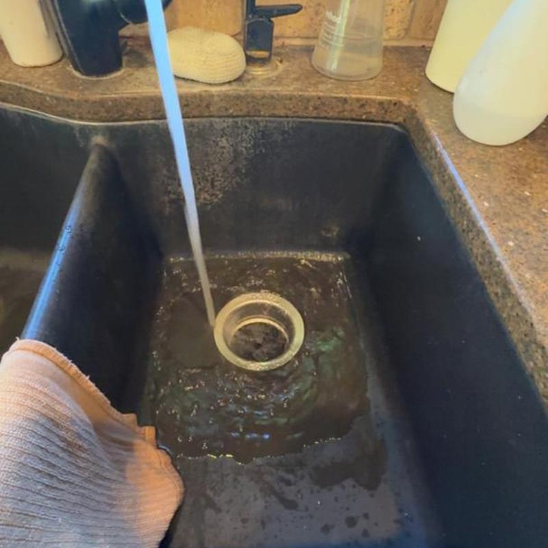 Kitchen sink drain with running water and towel nearby