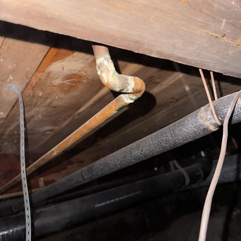 Old copper water pipe with corrosion in crawl space