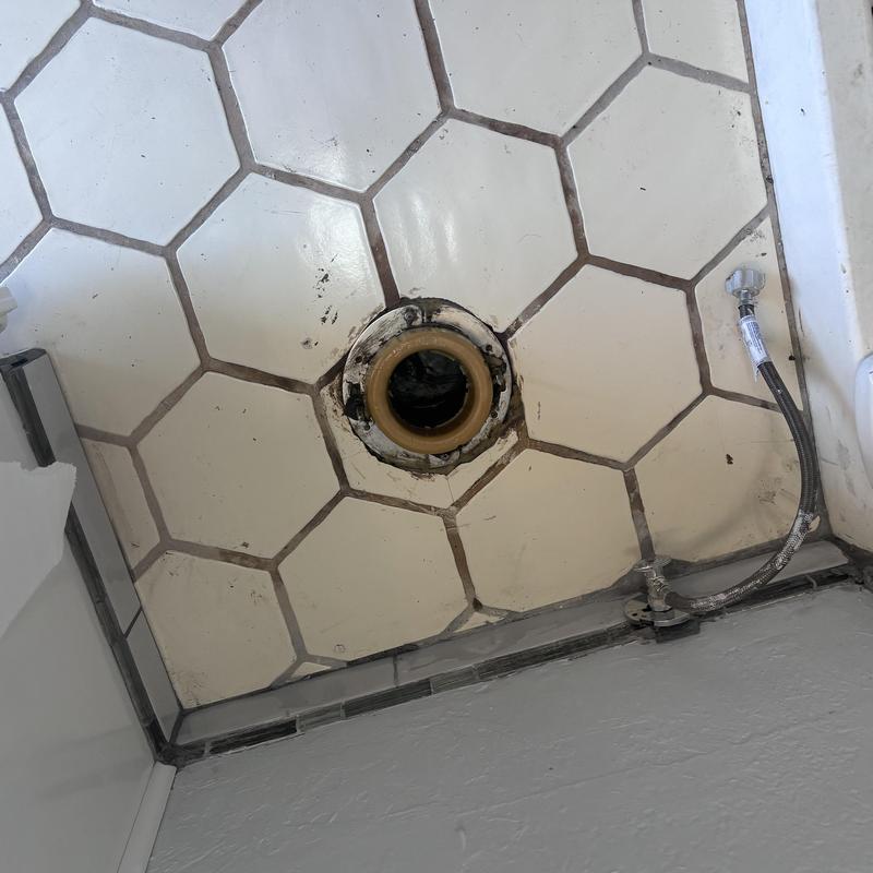 Toilet flange on tiled floor with water supply line disconnected