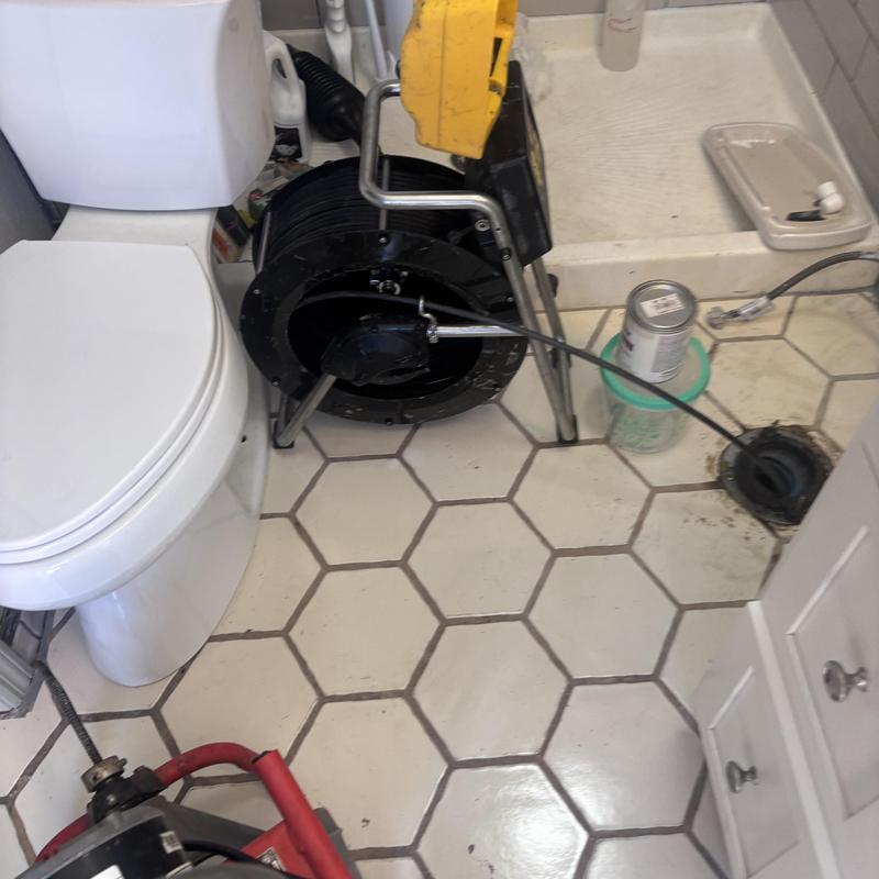 Toilet drain cleaning machine with drain snake in bathroom