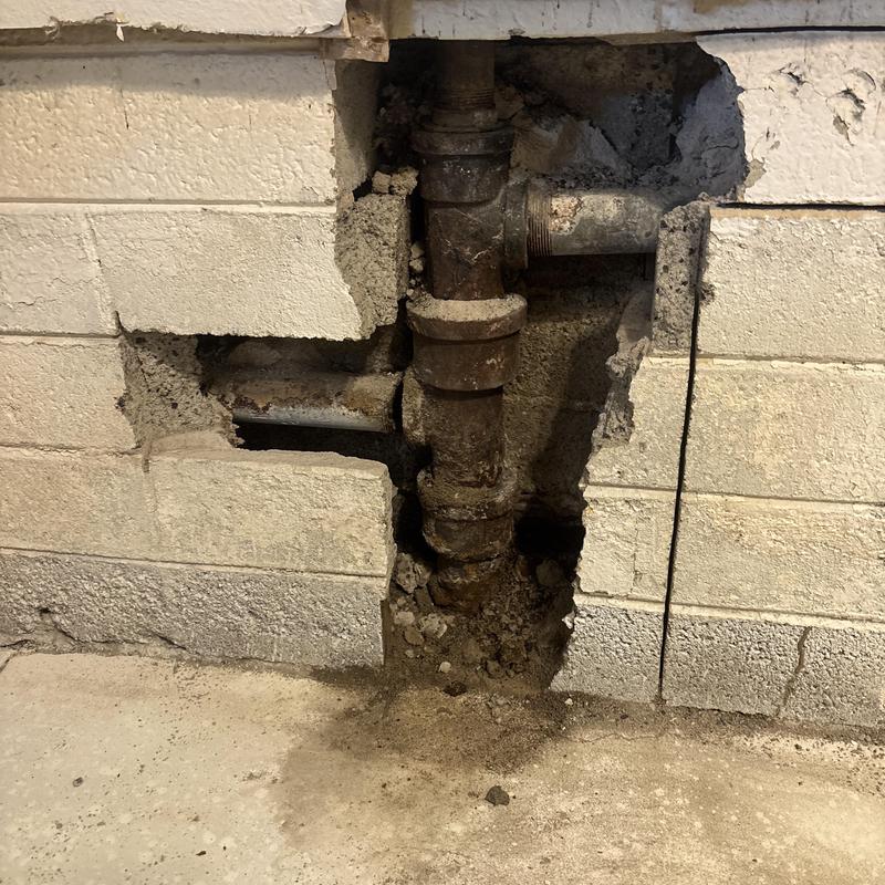 Cast iron drain pipe exposed in masonry wall repair