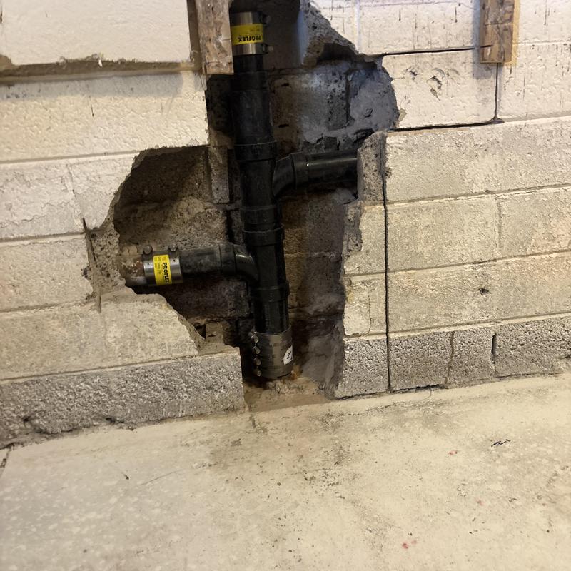 PVC drain pipe installation in basement wall cavity