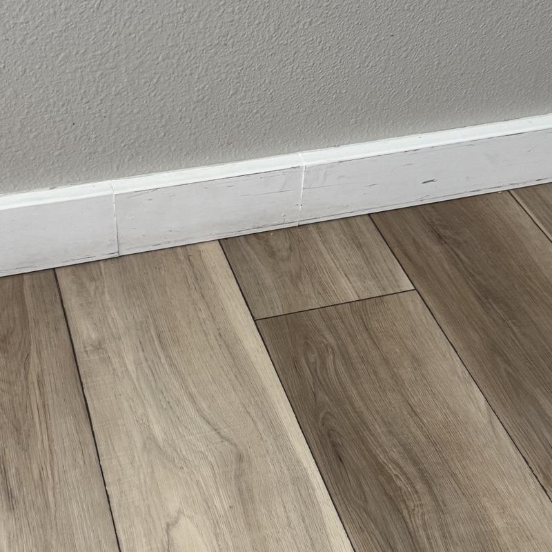 LVP flooring buckling near baseboard with moisture damage