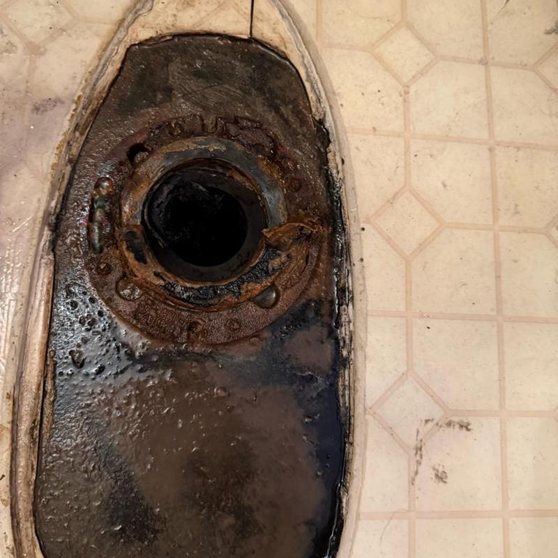 Toilet flange with rust and water damage on floor Toilet flange with rust and water damage on floor