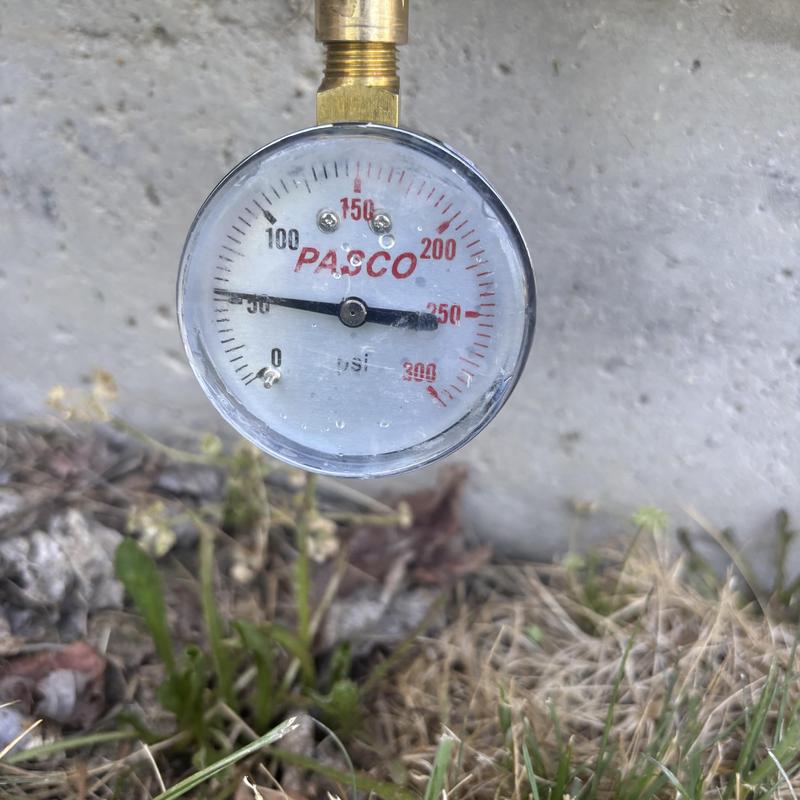 Water pressure gauge showing 50 psi outside home wall