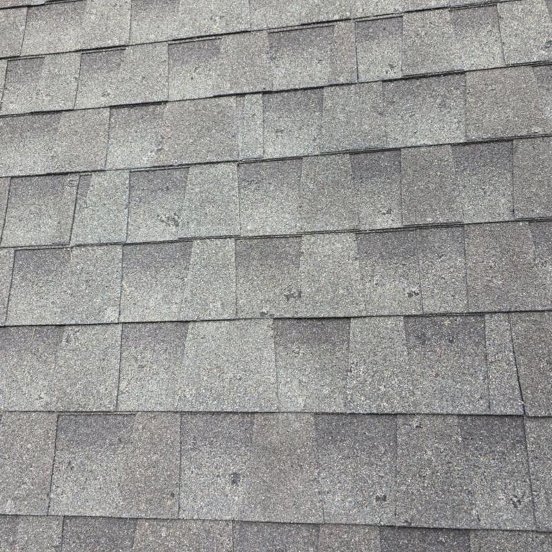 Asphalt roof shingles with visible hail damage spots