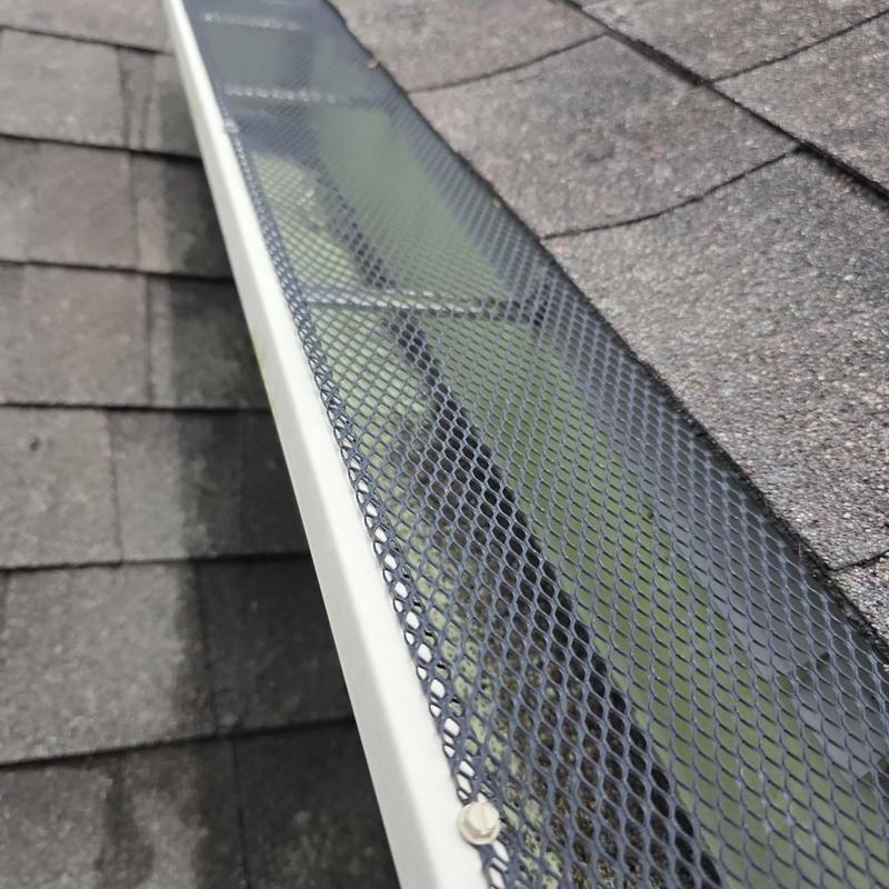 Gutter mesh guard installed on shingled roof edge
