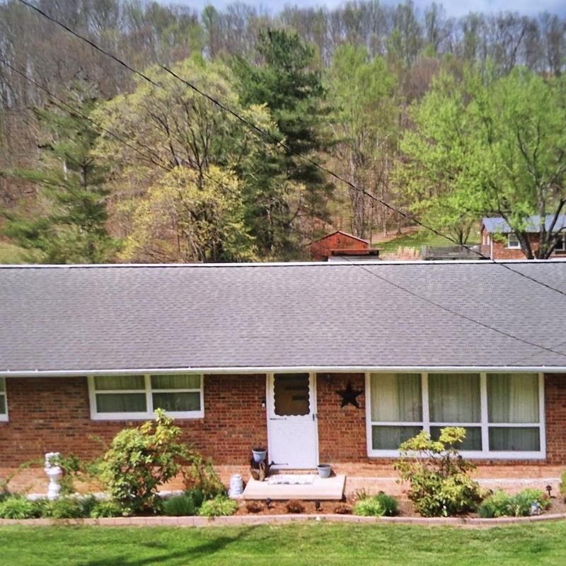 Asphalt shingle roof on brick house with greenery Asphalt shingle roof on brick house with greenery