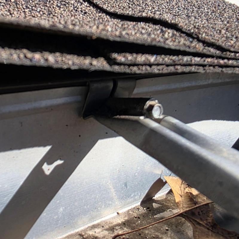 Roof shingle edge and metal gutter attachment under inspection