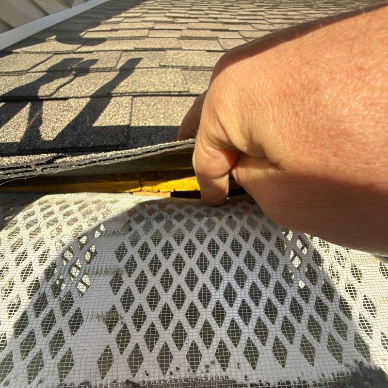 Roof shingles lifted to inspect hail damage and flashing