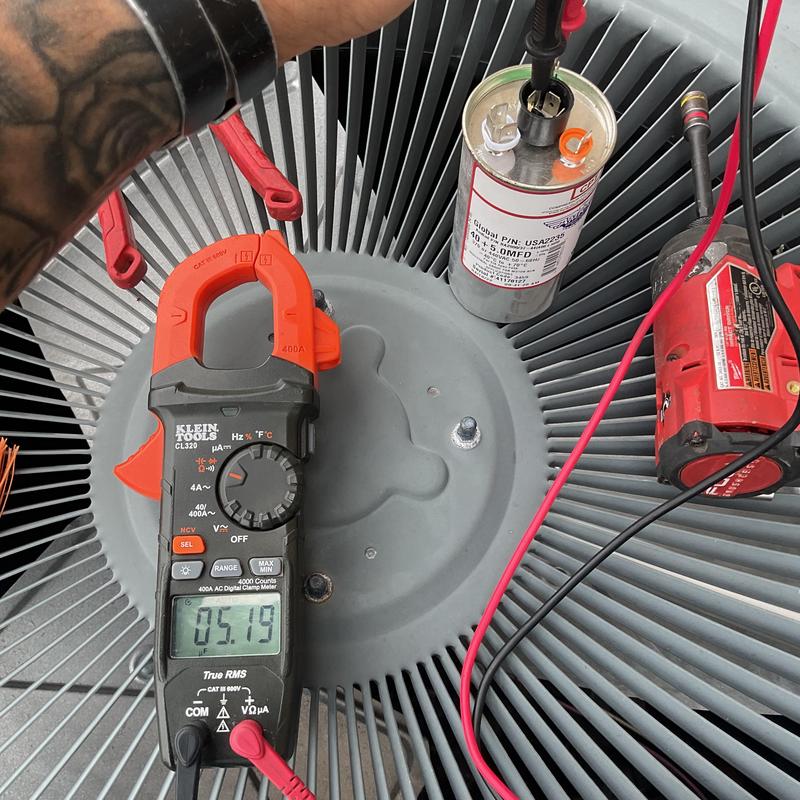 Condenser coil with clamp meter testing electrical components Condenser coil with clamp meter testing electrical components