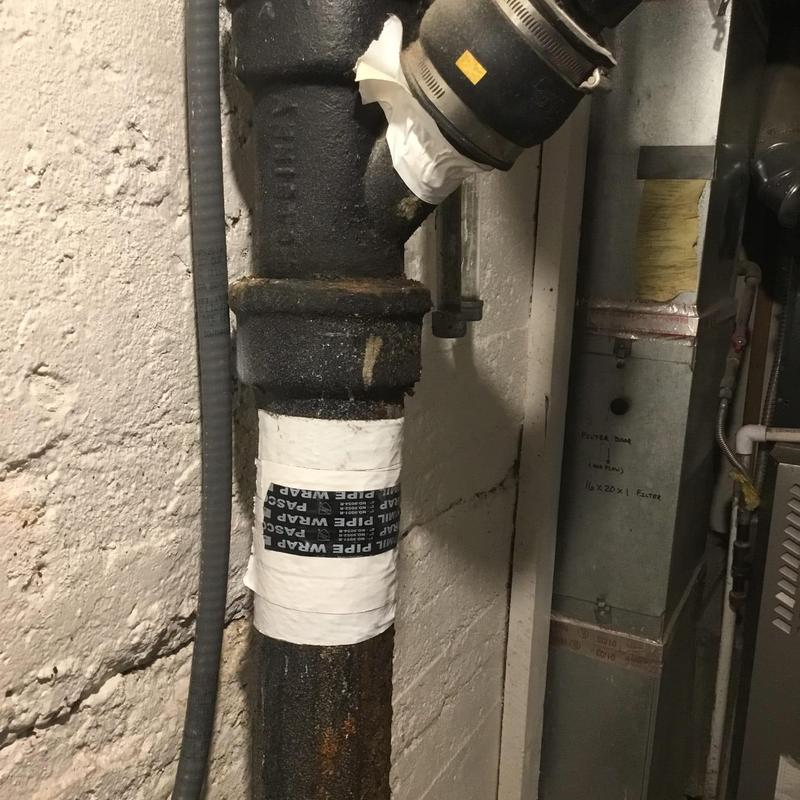 Cast iron plumbing pipe with wrap patch in basement wall Cast iron plumbing pipe with wrap patch in basement wall