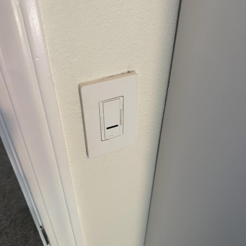 Dimmer light switch on beige wall near doorframe