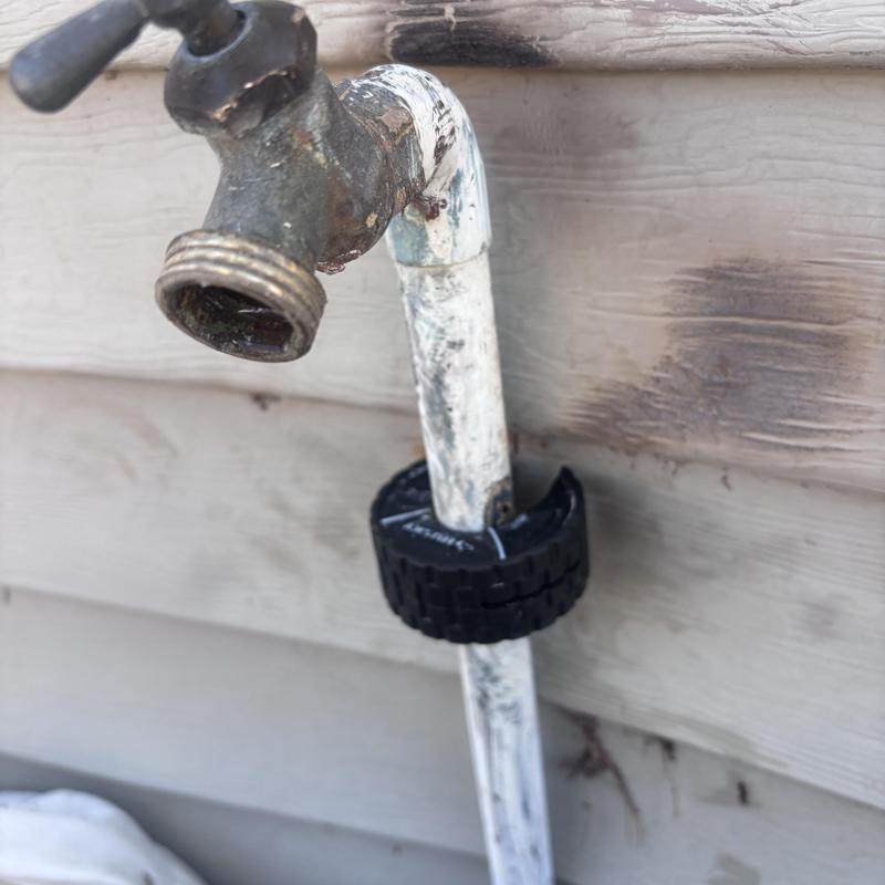 Outdoor hose bib with attached white pipe and clamp
