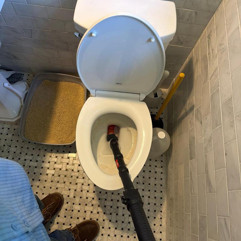 Toilet auger clearing clog in bathroom restroom