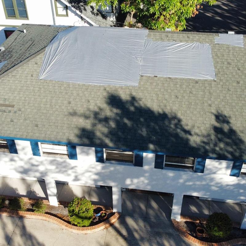 Roof shingles covered with emergency tarp after wind damage