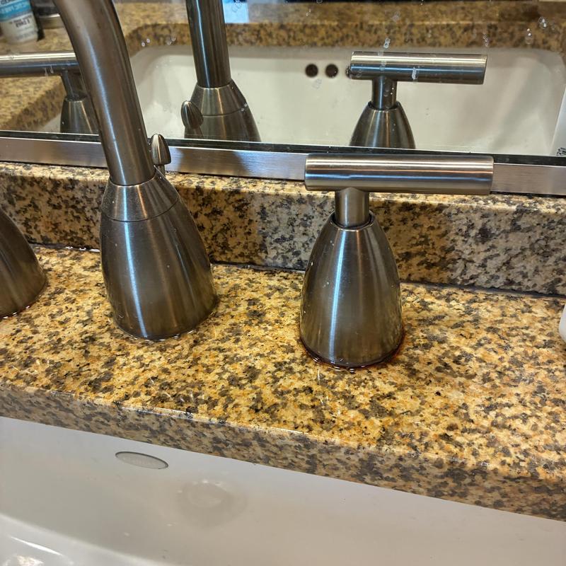 Basin sink faucet handle with leak residue on granite