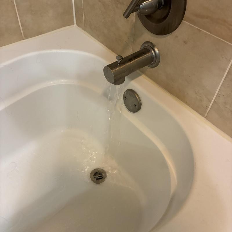 Bathtub spout with water flowing during repair in bathroom
