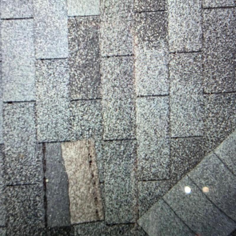 Asphalt roof shingles with damaged and replaced areas