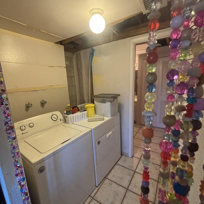 Washing machine hookups in laundry room with dryer nearby