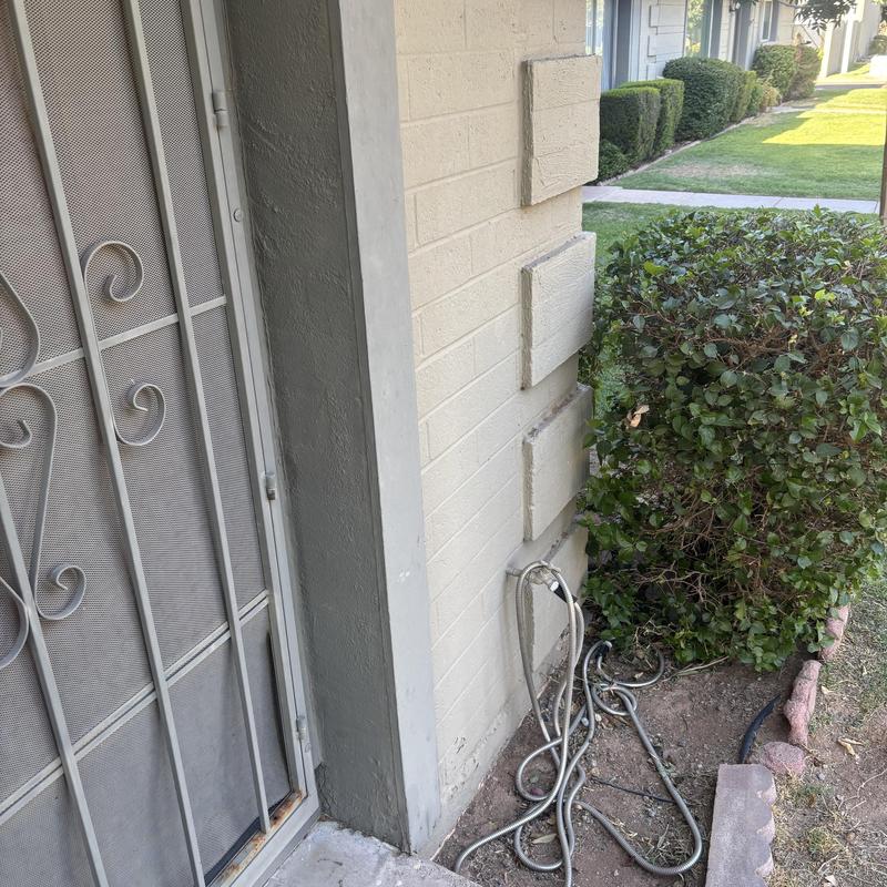 Outdoor water supply line near residence wall and bushes