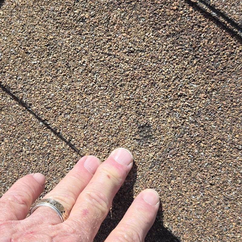 Asphalt shingle roofing with hail damage impact mark