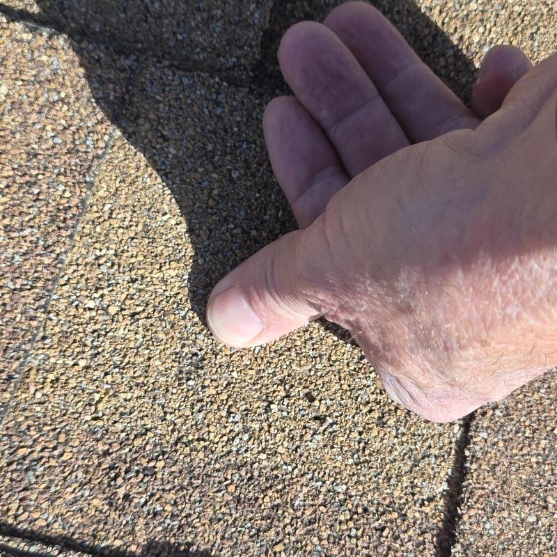 Roof shingles showing hail damage close-up with hand