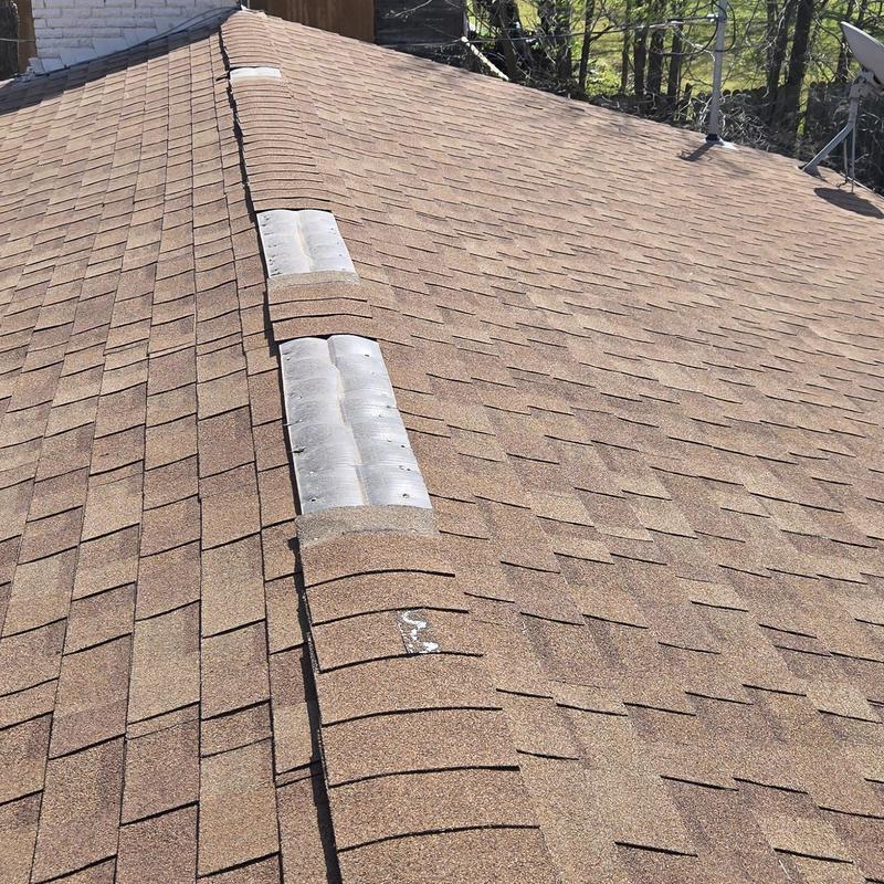 Asphalt shingle roof with hail damage on ridge vents