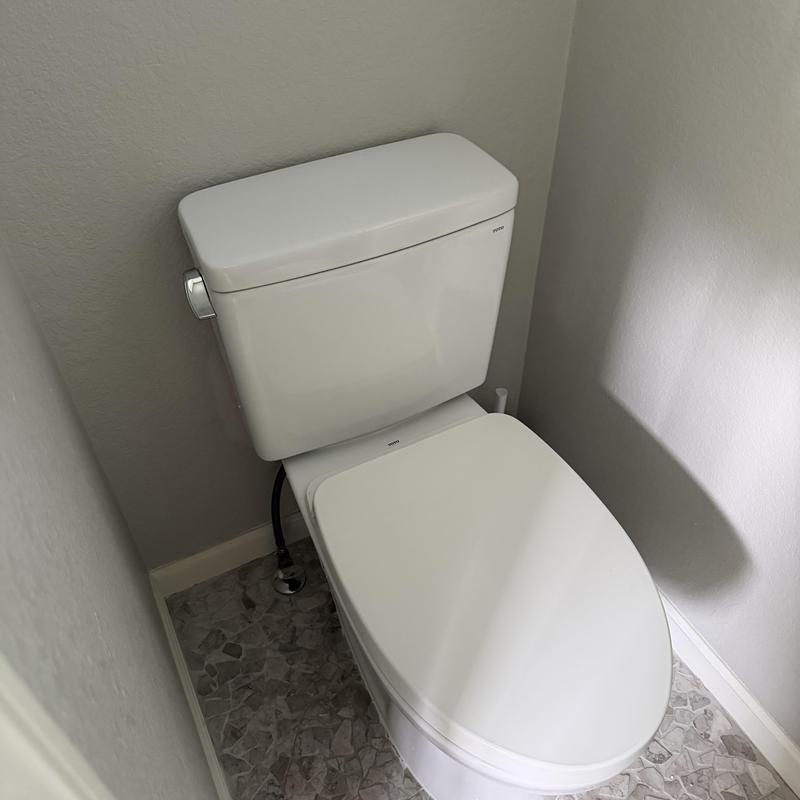 Toilet installed in corner bathroom with tiled floor Toilet installed in corner bathroom with tiled floor