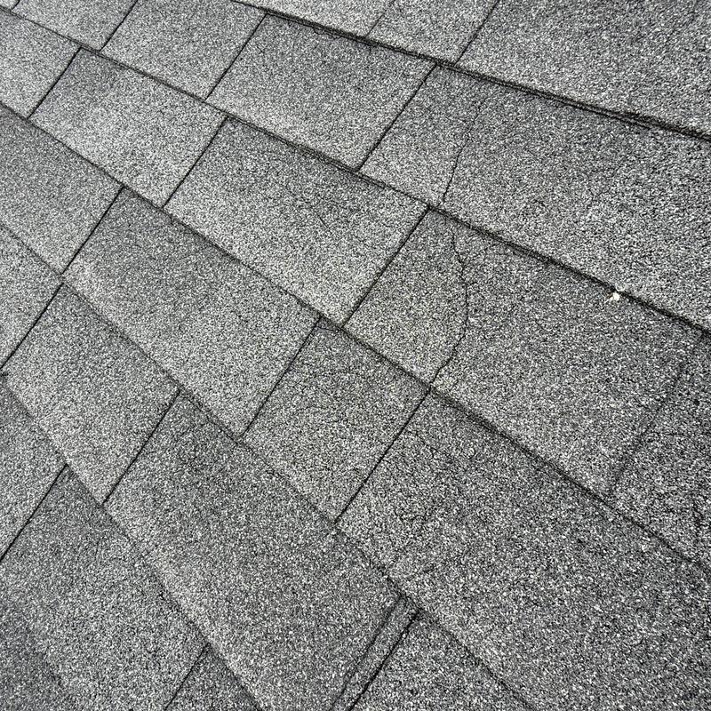 Asphalt shingle roof with visible cracks close-up