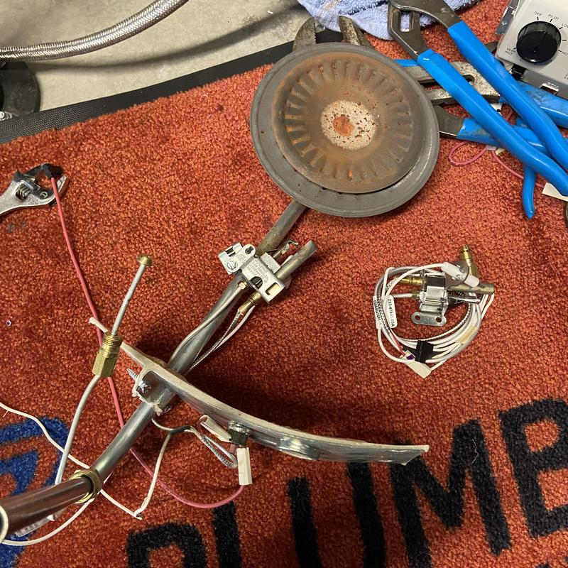 Water heater burner assembly with ignition parts on floor