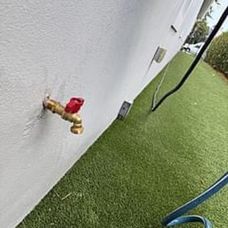 Outdoor hose bibb with red handle installed on wall