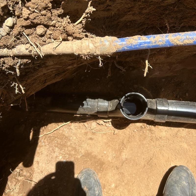 Main sewer line pipe exposed in dirt trench