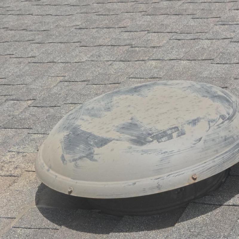 Skylight cover on asphalt shingle roof showing wear