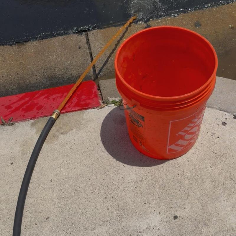 Commercial water heater flushing draining into bucket Commercial water heater flushing draining into bucket