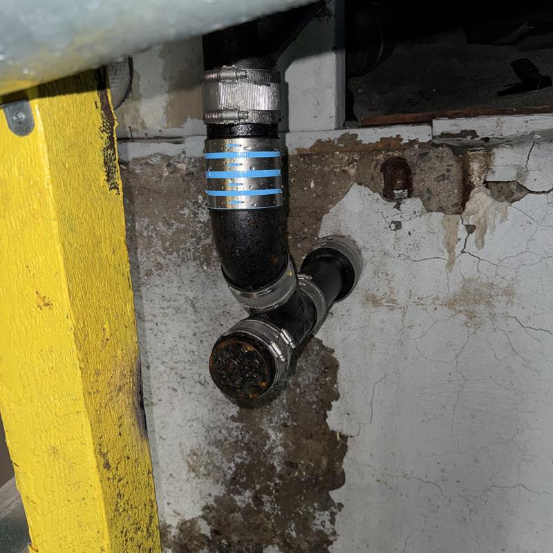 Basement main drain line with cleanout cap and clamps