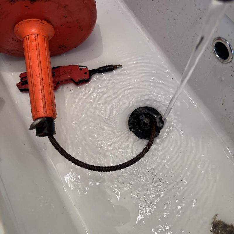 Basin drain with snake tool clearing hair clog