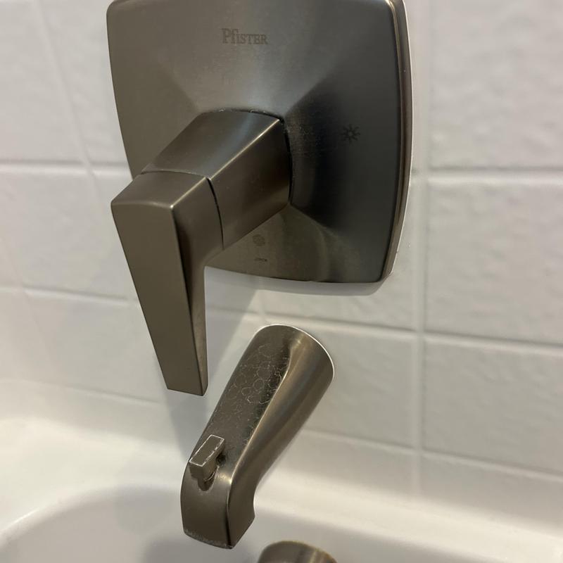 Shower valve handle and tub spout in bathroom wall