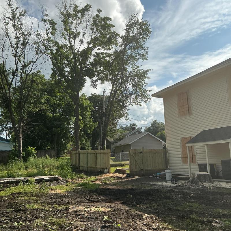 Tree stump removal near house with wooden fence Tree stump removal near house with wooden fence