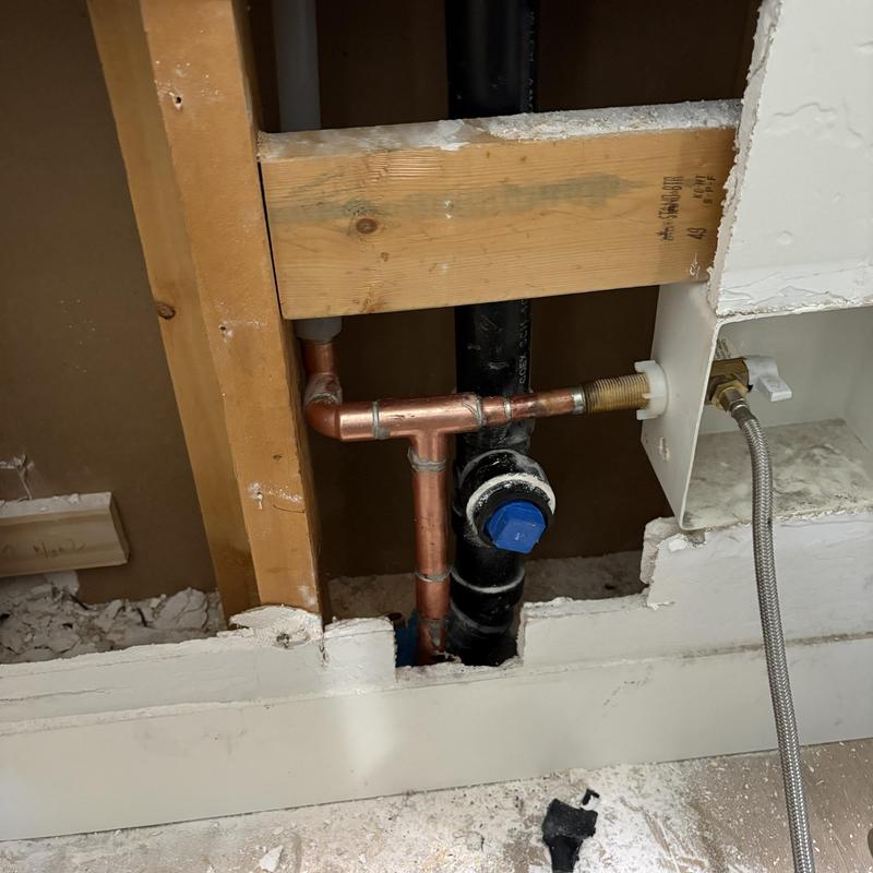 Copper plumbing drain line with fittings inside wall cavity