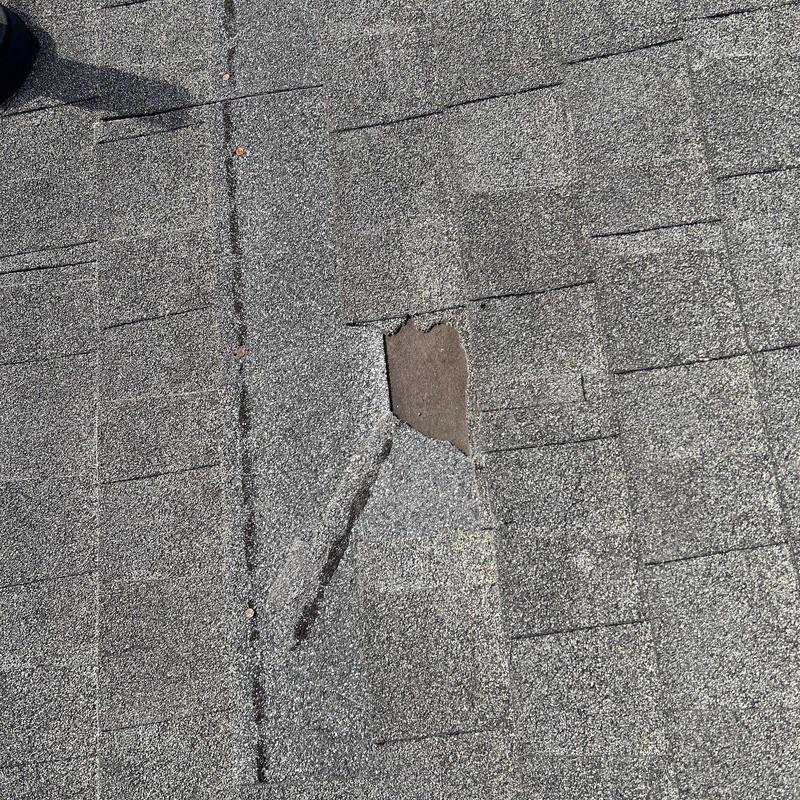 Asphalt roof shingle with hail damage hole