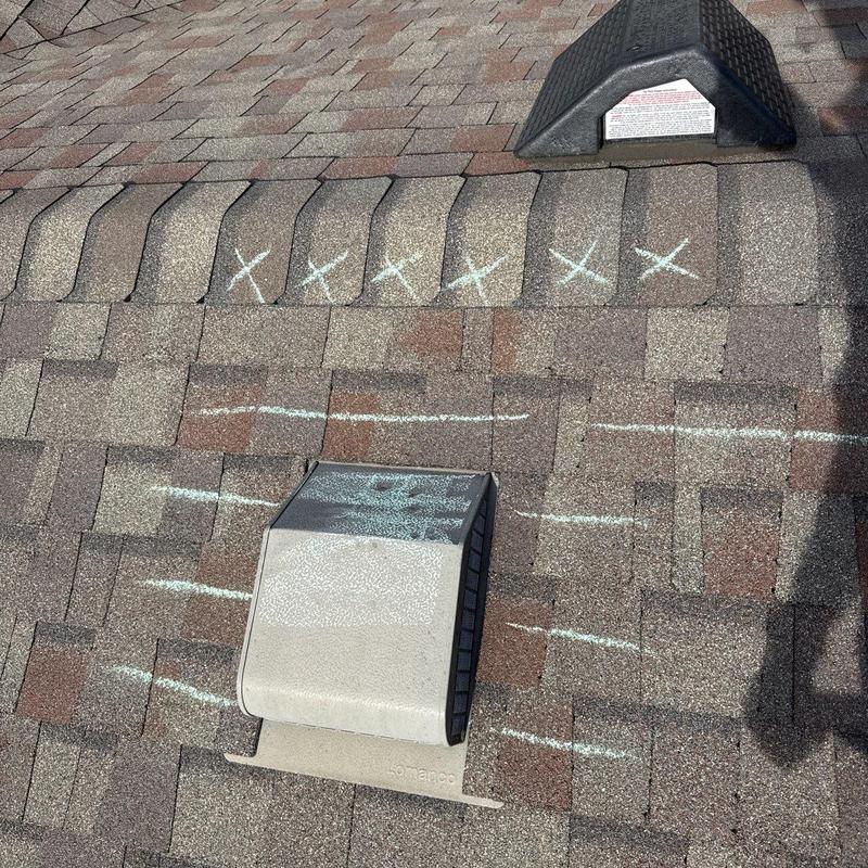 Ridge vent hail damage with chalk markings on shingles